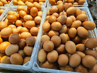 Trays of fresh brown eggs arranged in a market display. Suitable for egg industry visuals, kitchen...