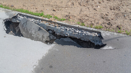 A sinkhole in the asphalt. Poor-quality asphalt pavement. Destruction of the road surface as a...
