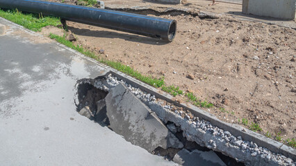A sinkhole in the asphalt. Poor-quality asphalt pavement. Destruction of the road surface as a result of soil erosion. Danger of asphalt sinkhole. Cracks in water pipes lead to soil erosion.
