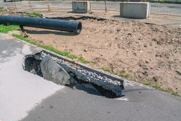 A sinkhole in the asphalt. Poor-quality asphalt pavement. Destruction of the road surface as a result of soil erosion. Danger of asphalt sinkhole. Cracks in water pipes lead to soil erosion.