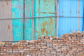 blue sky with wall A bricks stone with blue corrugated iron metal fence / Zinc wall,  traditional grungy door of Indian village house, stack of bricks close up