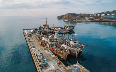 Abandoned vessels docked at a quiet harbor under a cloudy sky in early morning light