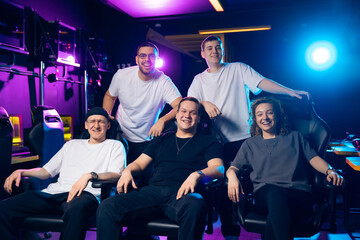 Obraz premium Portrait happy team of esports. Diverse group of young adults enjoying gaming in neon-lit room