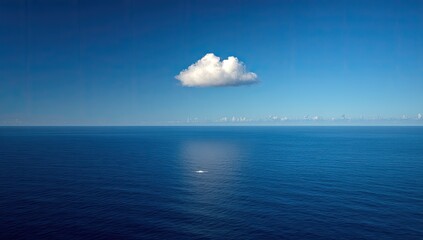 Vast ocean expanse, single puffy white cloud against clear blue sky