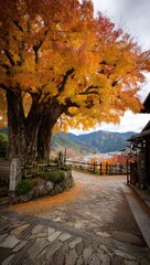 Autumnal path beneath a vibrant maple tree, leading to a mountain village