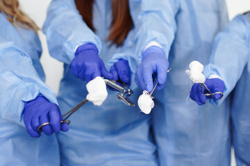 Doctors hold surgical instruments with bandages in their hands.