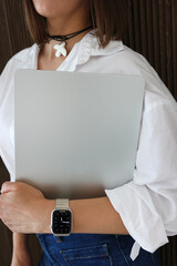 A woman with an electronic watch holds a laptop in her hand.