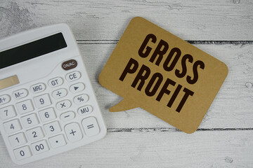 Gross Profit (GP) text with calculator on wooden background