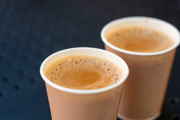 Masala chai an Indian street restaurant, spiced milk tea in paper cup, traditional hot drink