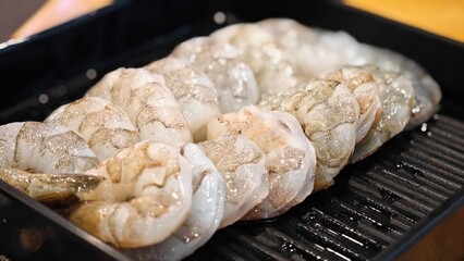 Fresh peeled raw shrimp served on black tray.
