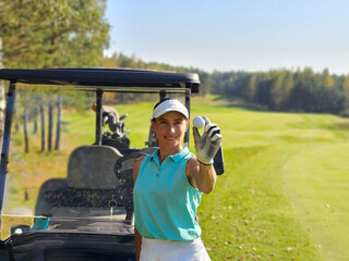 Golfer smiling while holding a golf ball near a golf cart