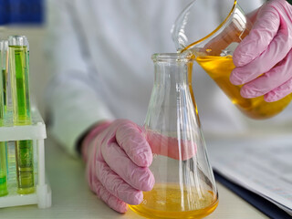 Scientist in laboratory conducts chemical experiment using glassware and colorful liquids