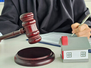 Court judge reviewing real estate matter with gavel and house on desk during legal proceedings