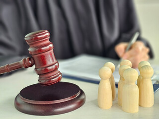 Legal proceedings involving wooden figures and a gavel on a desk highlighting courtroom