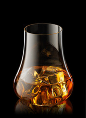 Glass of scotch whiskey and ice isolated on black background with clipping path