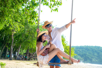 Romantic lifestyle asian couples lover playing an ukulele on the hammock. relax and honeymoon in luxury resort near the beach. Thailand. Summer,Travel, Valentine Concept.