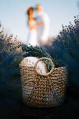 Couple embracing among lavender plants with a woven basket in the foreground