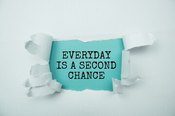 Everyday Is A Second Chance message written on blue paper with torn paper background