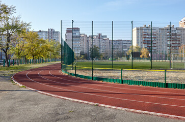 Red treadmill on sport field. Landscape of soccer field with green grass and running track