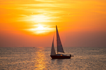 Fototapeta premium Sailing boat silhoutted against the orange sky