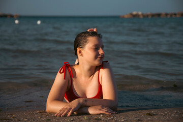 Pretty girl wearing red swimsuit resting on the beach,  summer vacations