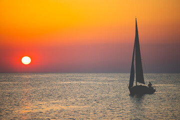 Sailing boat silhoutted against the orange sky
