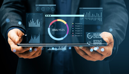 Businessman holding tablet with digital financial analysis dashboard, charts, and KPI infographics on futuristic virtual interface display.