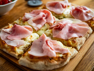 Pinsa romana with boiled ham on wooden board, close-up