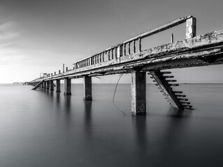 Black and white landscape photo of a pier on a beach in Tien Giang province, Vietnam. Long exposure...