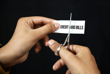 Cutting credit card bills concept background with hand using scissors to cut paper.