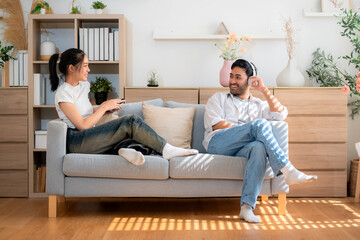 Happy young asian couple relax sitting on sofa smiling and enjoy a cheerful conversation in cozy...