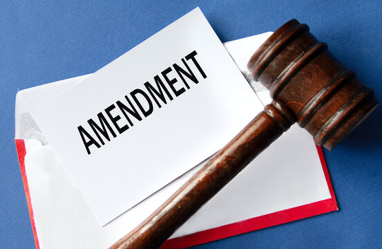 AMENDMENT - word on a white sheet of paper against the background of an envelope and a judge's gavel