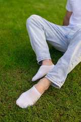 Male foot in white sock on the background of grass. Man foot with sock on.