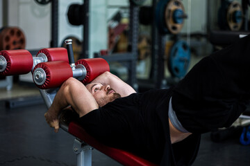 A muscular fitness trainer shows how to do exercise on a bench to build up his abdominal muscles....