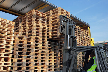 Counterbalance driver unloading empty euro pallets for local warehouse.