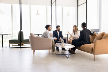Business partners coworkers of diverse ethnicities meet for informal team briefing in cozy shared...