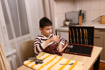 Boy wipes forks and kitchen knives. Housework.