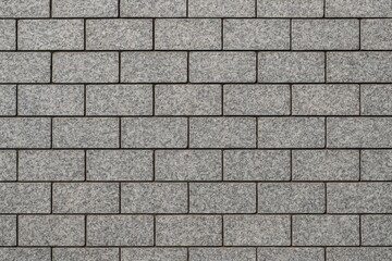 Obraz premium The pavement consists of rectangular gray granite tiles with a blurred background.
