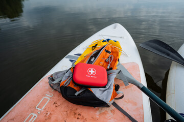 A bright red first aid kit is strategically placed on a paddle board, fully prepared for any...