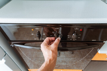 A person opens the oven door to retrieve delicious food or baked goods, highlighting a common,...