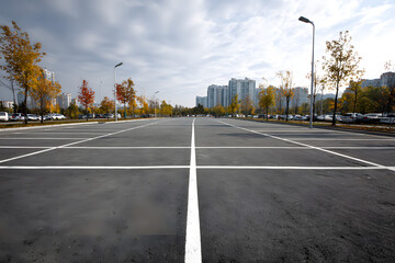 A clean and empty parking lot with a gray asphalt surface, lined with white markings, providing a neutral background for automotive advertising and product showcase.