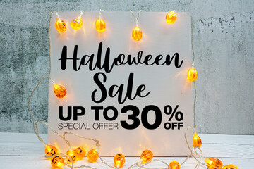 Halloween Sale 30% off text with LED pumpkin decoration on wooden background