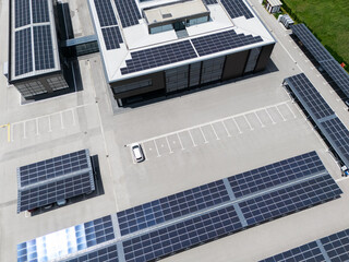 Aerial view of building with solar panels on a roof and parking space with solar canopies