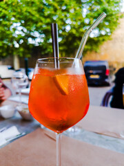 A glass of alcoholic Spritz made from sparkling white wine, accompanied by ice cubes and a slice of...