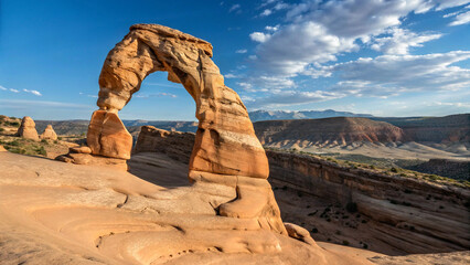 Natural rock, arch like structure composed of smooth, light brown sandstone with visible stratification at peak of mountain.
