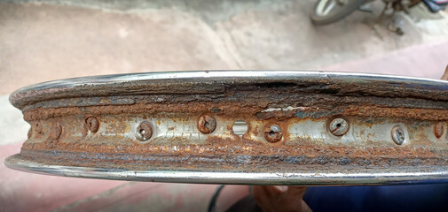  A Close up view of a Motorcycle wheel rim seen rusted, withered, damaged, worn out and unfit for...