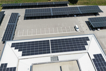 Aerial view of building with solar panels on a roof and parking space with solar canopies
