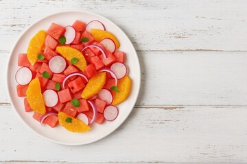 Fresh watermelon and citrus salad with radish and red onion on rustic wooden surface. Summer organic dish with empty space for text.