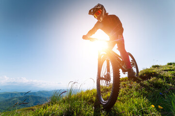 Cyclist man on mountain bike outdoors. Male tourist riding bicycle on grassy trail in mountains...