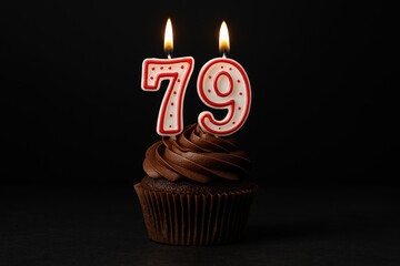 Celebratory cupcake with number 79 candles against a dark backdrop